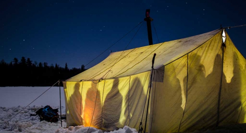 Shadows of people are illuminated through tent walls. 